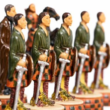 Peças de xadrez em fila representando guerreiros escoceses em kilt armados com espadas